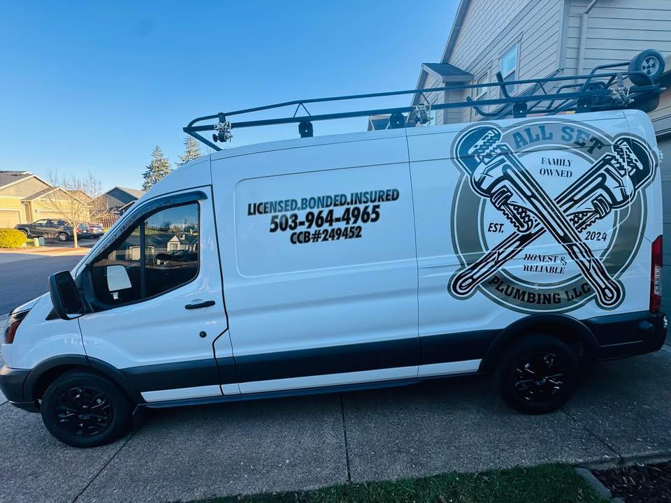 A white plumber service van with company branding, contact information, and license number is parked in a residential neighborhood driveway.